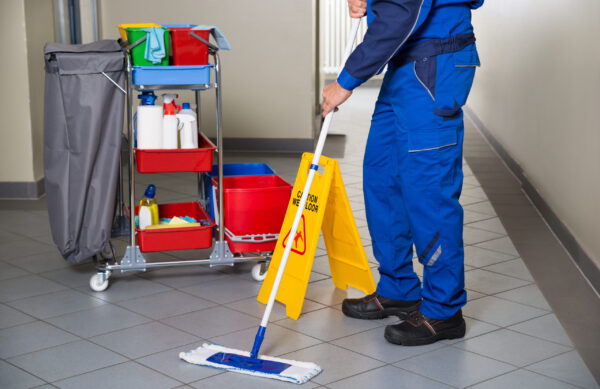 Low,Section,Of,Male,Janitor,With,Broom,Cleaning,Office,Corridor